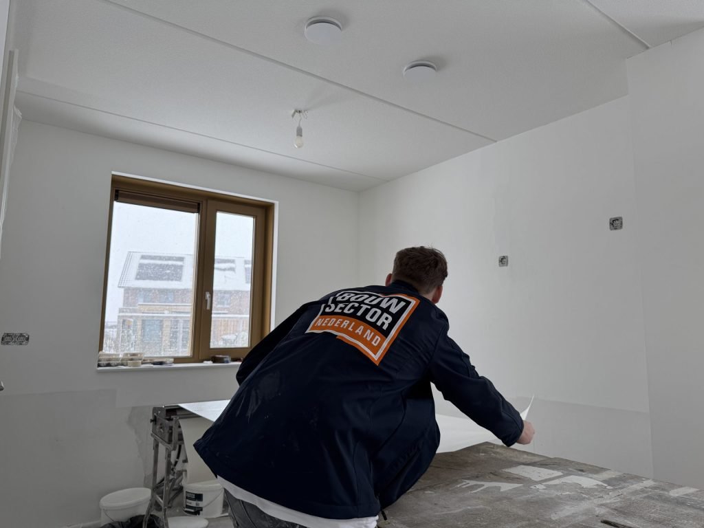 Vakman van Bouwsector Nederland werkt aan de plaktafel in een kale kamer
