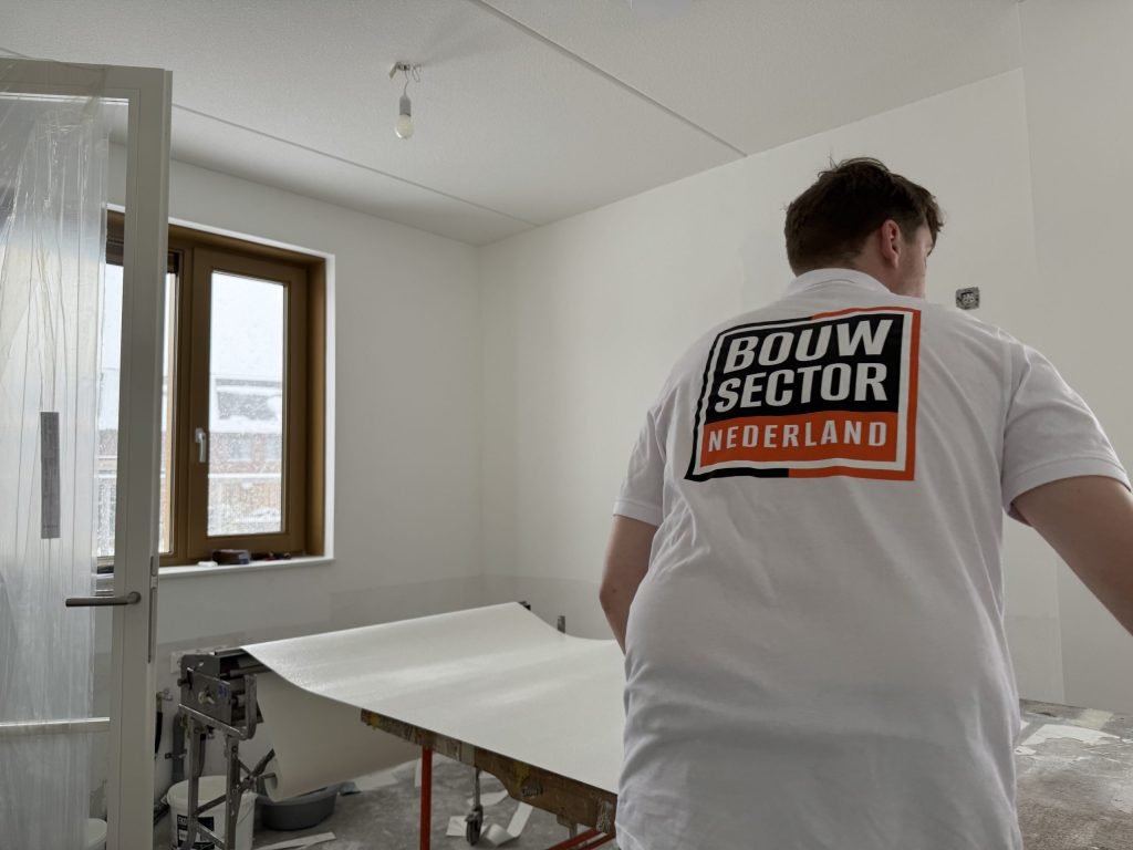 Behanger van Bouwsector Nederland bij de plaktafel met een baan behang